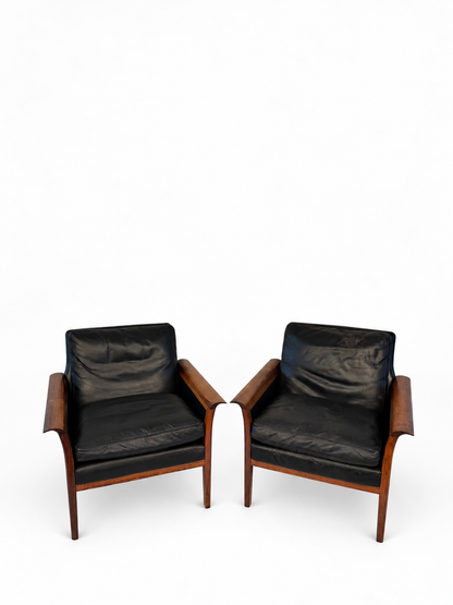 Pair of rosewood and black leather lounge chairs cataloged as Hans Olson, full front view