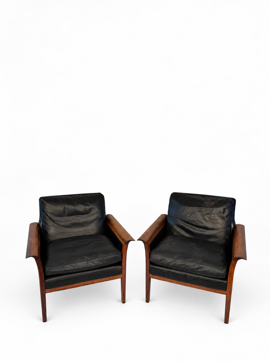 Pair of rosewood and black leather lounge chairs cataloged as Hans Olson, full front view