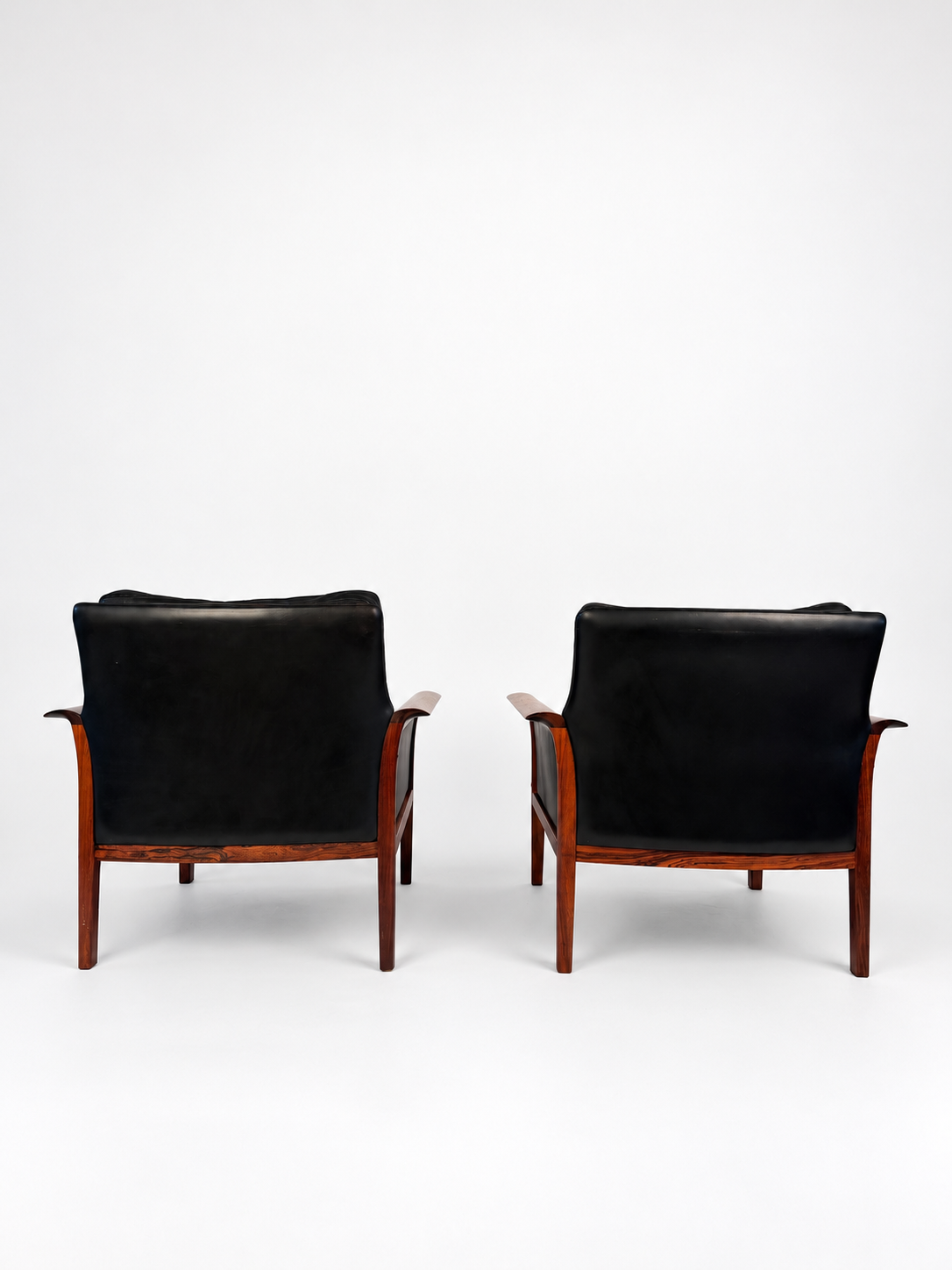 Rear view of the pair of rosewood and black leather lounge chairs