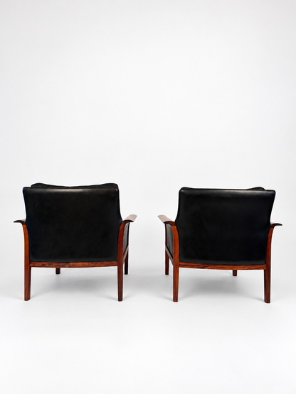 Rear view of the pair of rosewood and black leather lounge chairs
