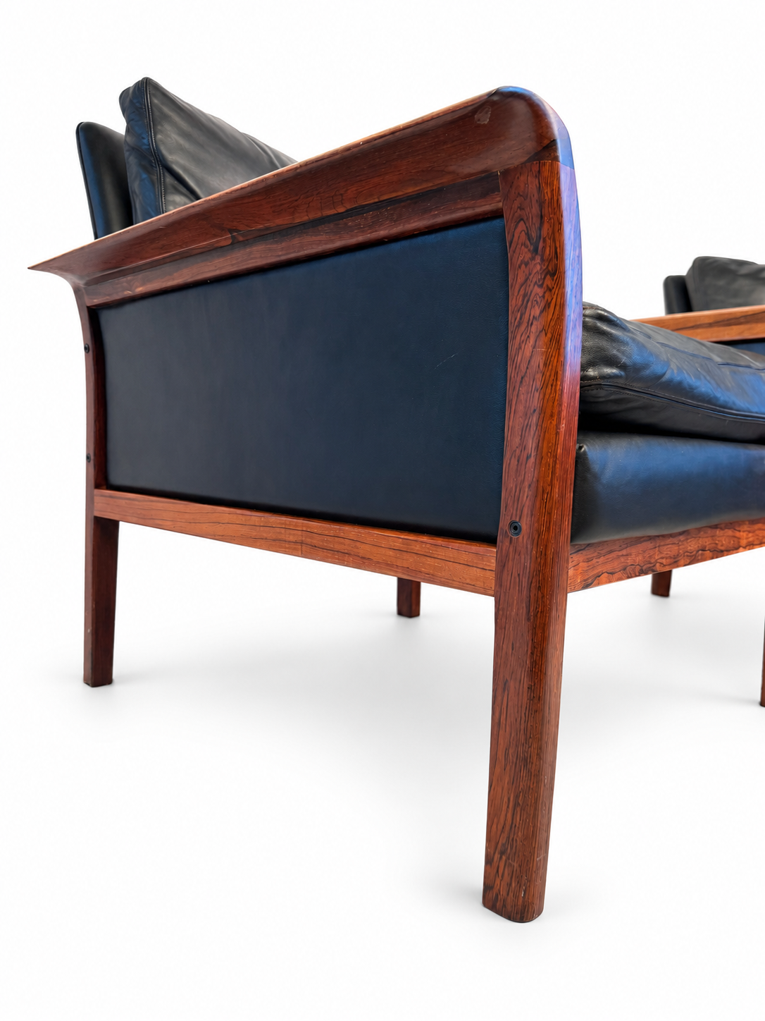 Side profile showing a lounge chair’s exposed rosewood frame and leather cushions