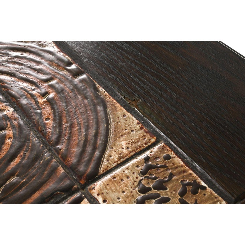 Closeup of the disclosed chip in the Ox Art tile beside the oak border of the Gangsø dining table